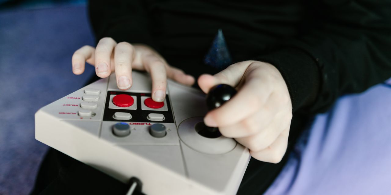 Hands gripping a retro gaming console joystick, showcasing classic gaming technology.