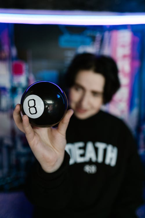 Free Person Holding a Black Billiard-ball with Number 8 Stock Photo