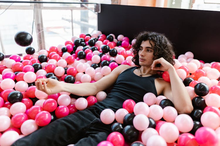 Man Lying On Plastic Balls In Dry Pool