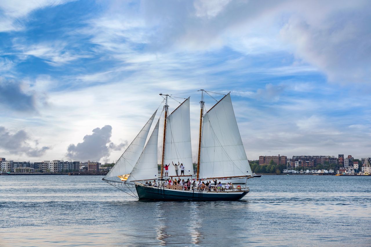 a classic schooner sailing in boston harbor with skyline in the backgr