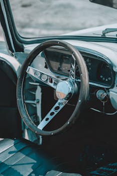 Close-up view of a vintage car interior showcasing a classic steering wheel and speedometer.
