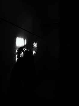 Silhouette of a person under dramatic lighting creating an eerie, mysterious ambiance.