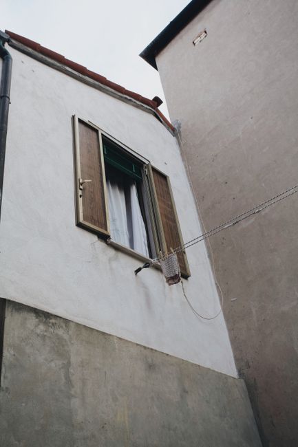 A charming Venetian window with wooden shutters and laundry line in Venice, Italy.