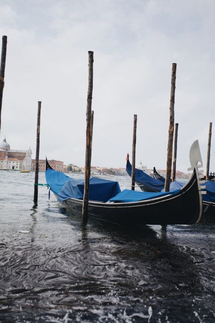 Traditional gondolas docked on the Venetian canals with iconic cityscape in the background.