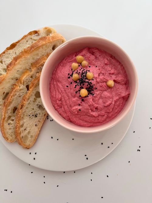 Free Delicious pink hummus garnished with seeds and chickpeas, served with artisanal bread. Stock Photo