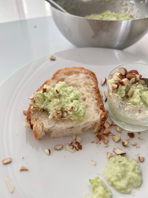 Free Slice of bread with creamy avocado spread topped with chopped nuts, perfect for breakfast or snack. Stock Photo
