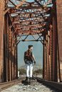 Man in Black Jacket Standing Beside Brown Metal Gate