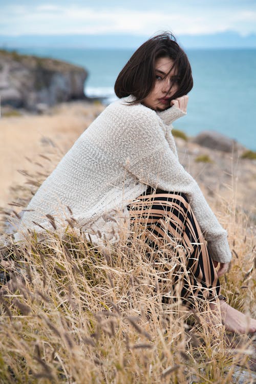 Close-Up Shot of a Woman in White Sweater Sitting on Grass
