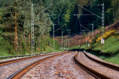 Free Railway track weaving through a dense, green forest, offering a serene transportation view. Stock Photo