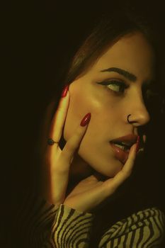 Close-up portrait of a fashionable young woman with dramatic lighting and stylish makeup.