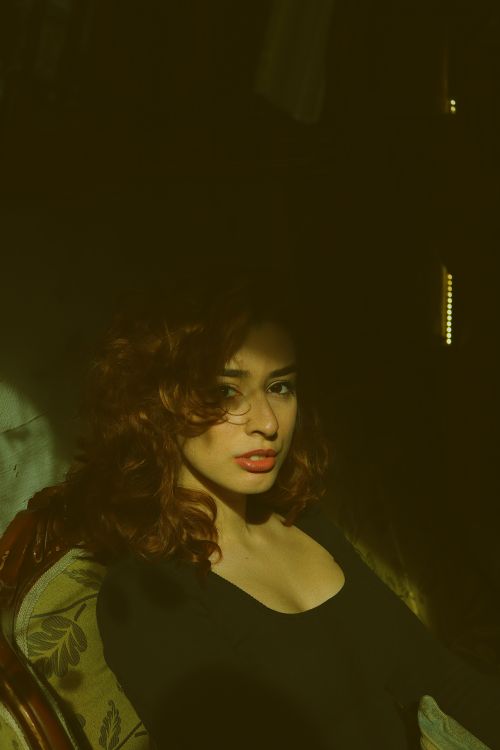 Free Close-up portrait of a woman with curly hair in artistic lighting. Stock Photo