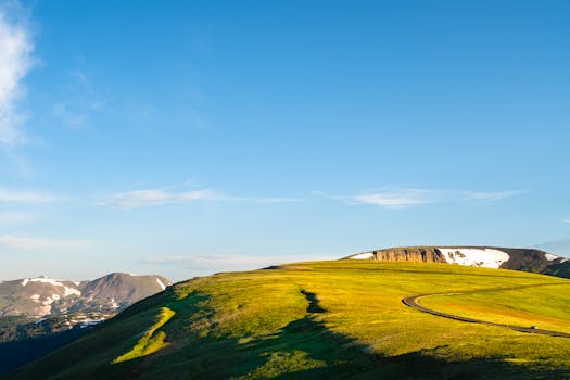 Breathtaking landscape of a sunlit grassy field and mountain range in Estes Park, Colorado.