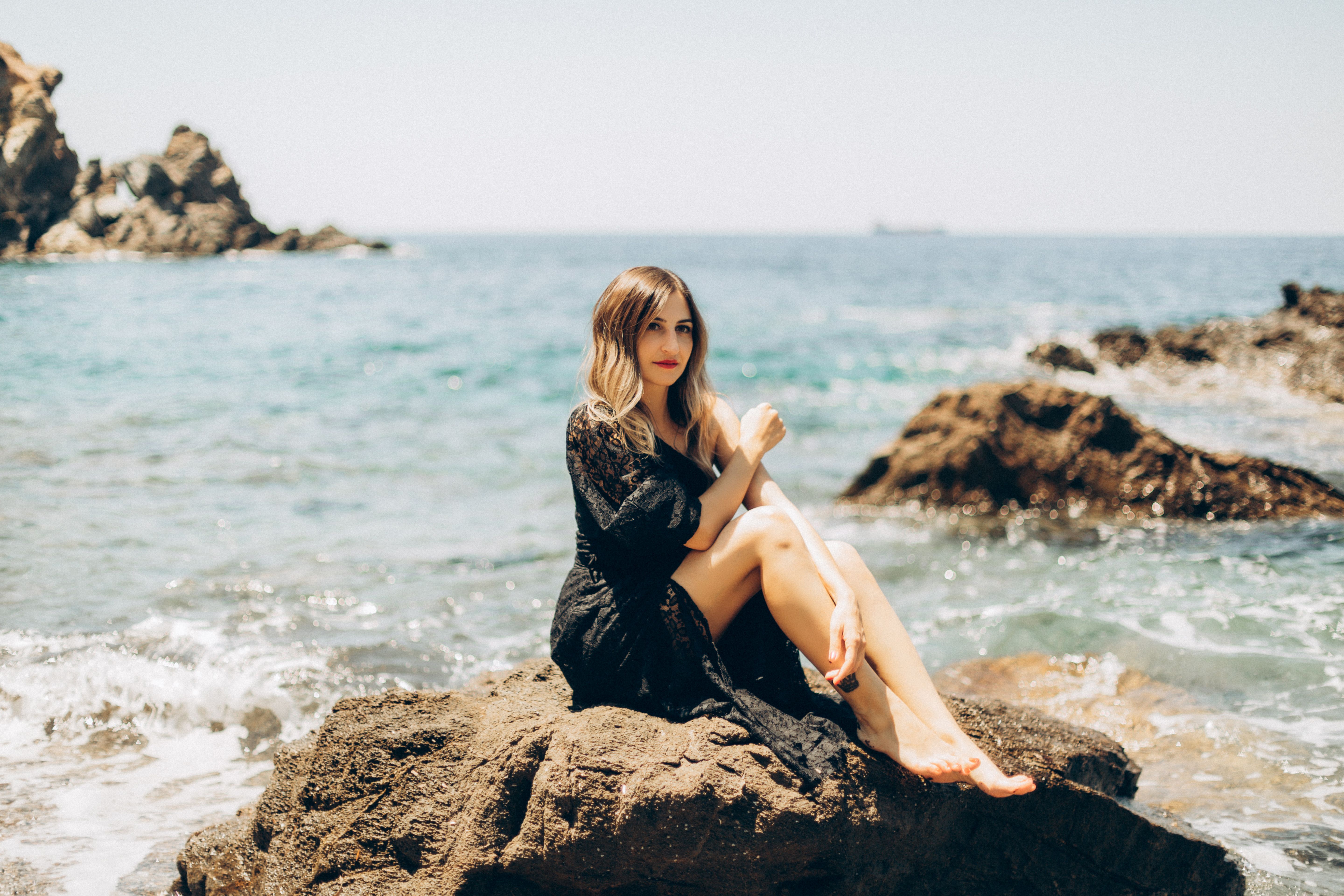 A Woman in Black Dress Sitting near the Sea · Free Stock Photo