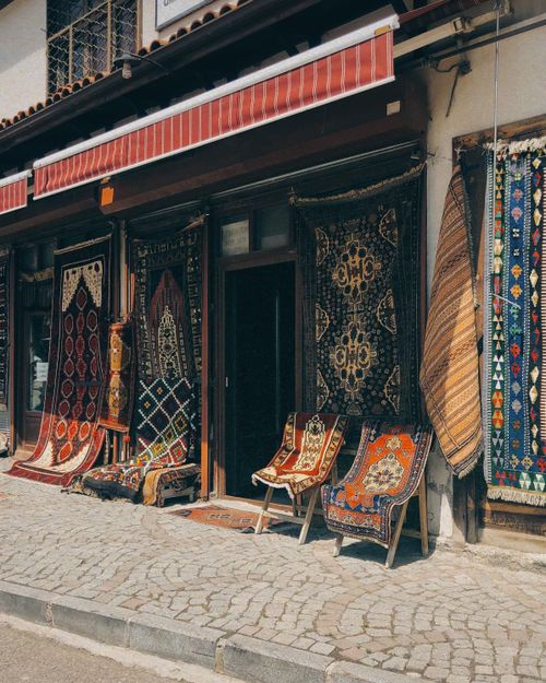 Free Vibrant display of traditional carpets outside a quaint shop on a city sidewalk. Stock Photo