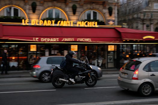 Motorcyclist riding past Le Depart Saint-Michel in Paris, captured with a panning effect for motion blur.
