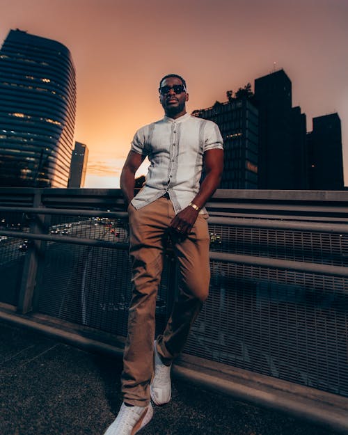 Man Wearing Brown Plants and White Polo Posing on the Railings