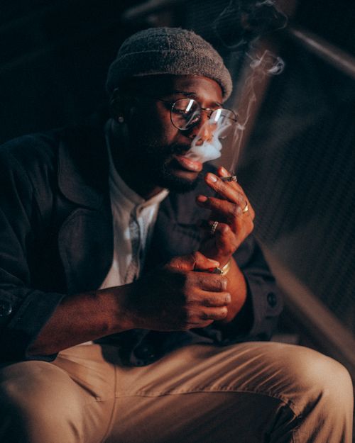 Free Close-up of a fashionable man smoking a cigarette, exuding a relaxed and contemplative vibe. Stock Photo