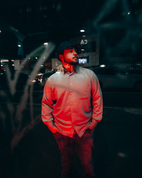 A Man in White Long Sleeves Standing on the Street at Night