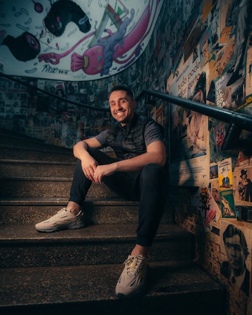 Man in Gray Shirt and Black Pants Smiling while Sitting on Stairs