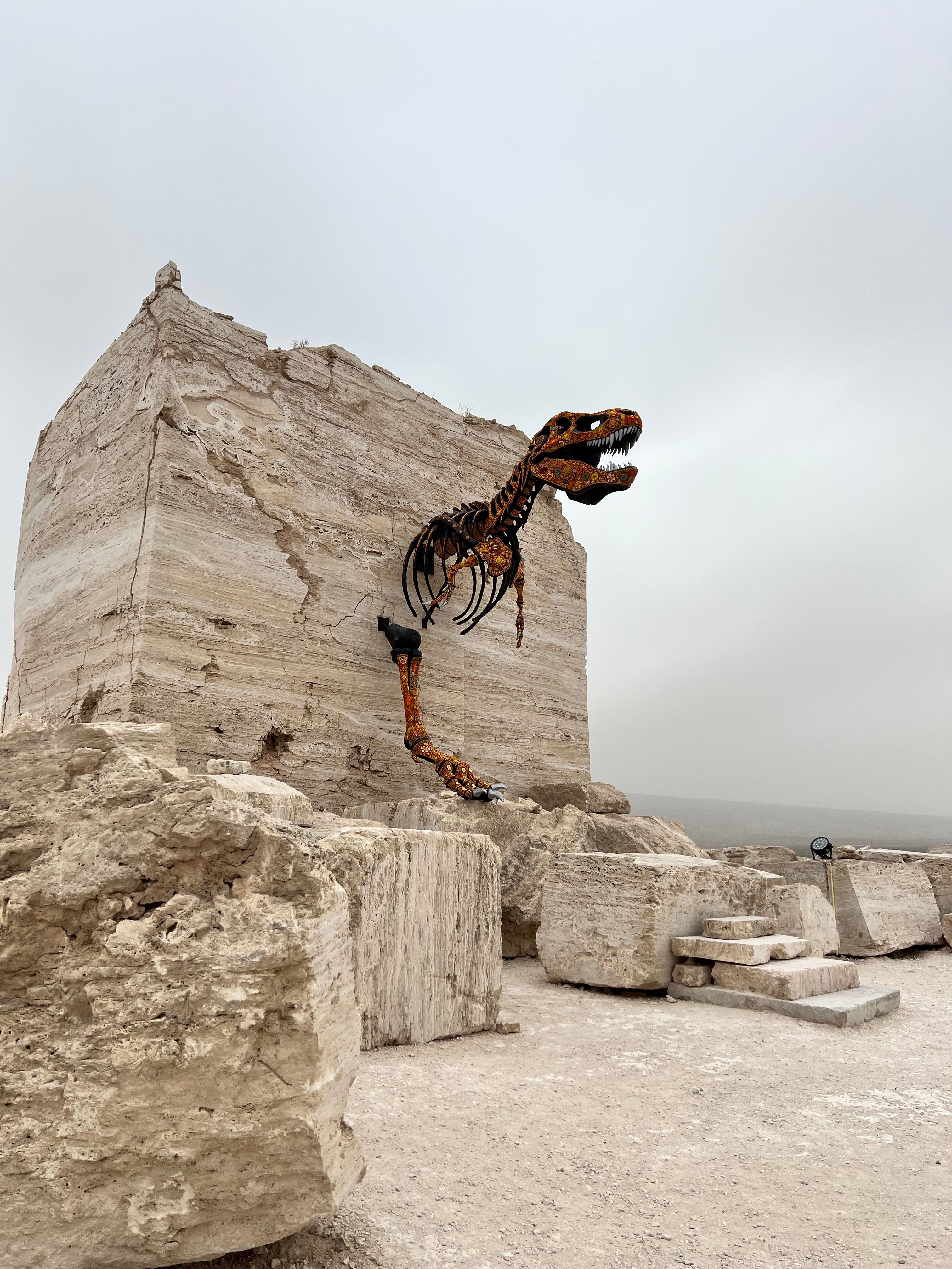 A dinosaur skeleton sculpture integrated into a dramatic rock formation at a quarry in Mexico.