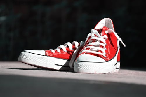 Неглубокая фотография пары красных низких кроссовок