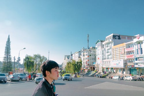 Pria Berjalan Di Jalan Menghadap Gedung Di Bawah Langit Biru