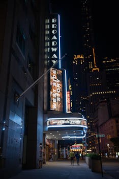A vibrant night view of Broadway Theater in New York City featuring West Side Story signage.
