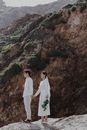 Man and Woman in White Long Sleeve Dress Standing on Brown Rock Formation