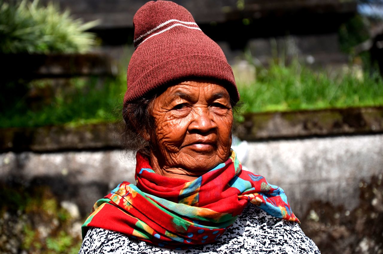 Senior woman wearing a red knit winter hat and colorful scarf