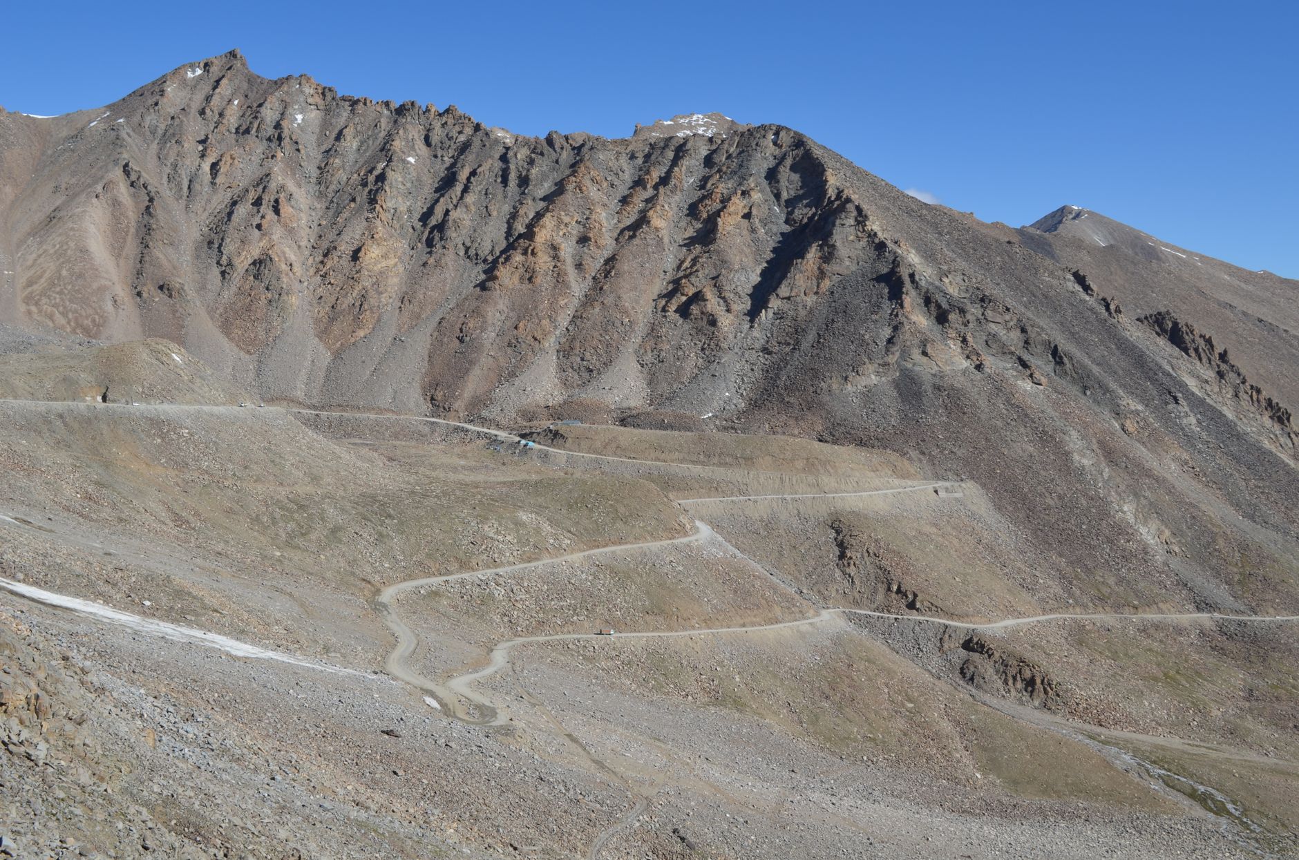 Himalayan road near Ladakh with military trucks, stark mountains, and cold blue afternoon light