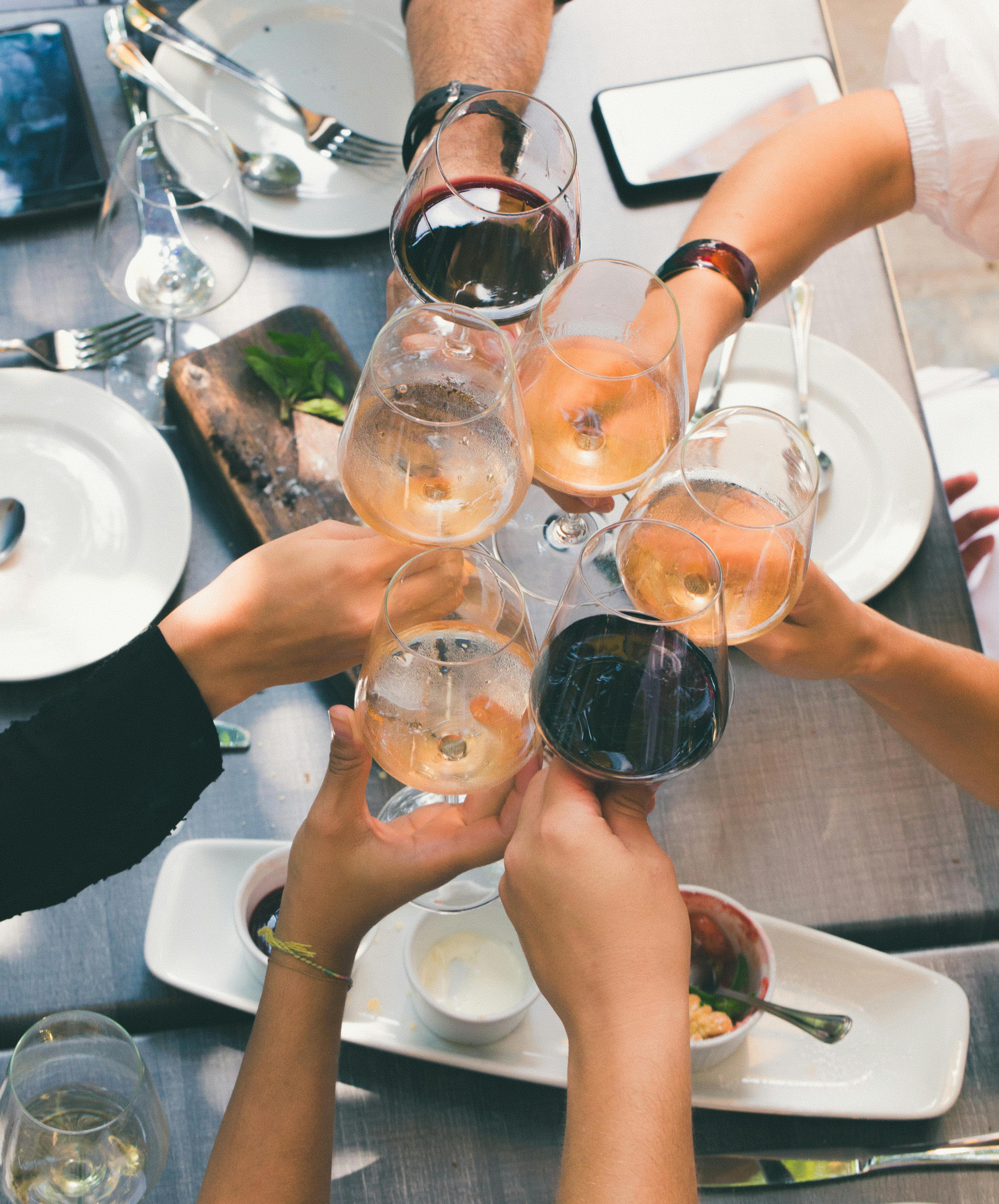 Friends raising glasses for a celebratory toast during a meal indoors.