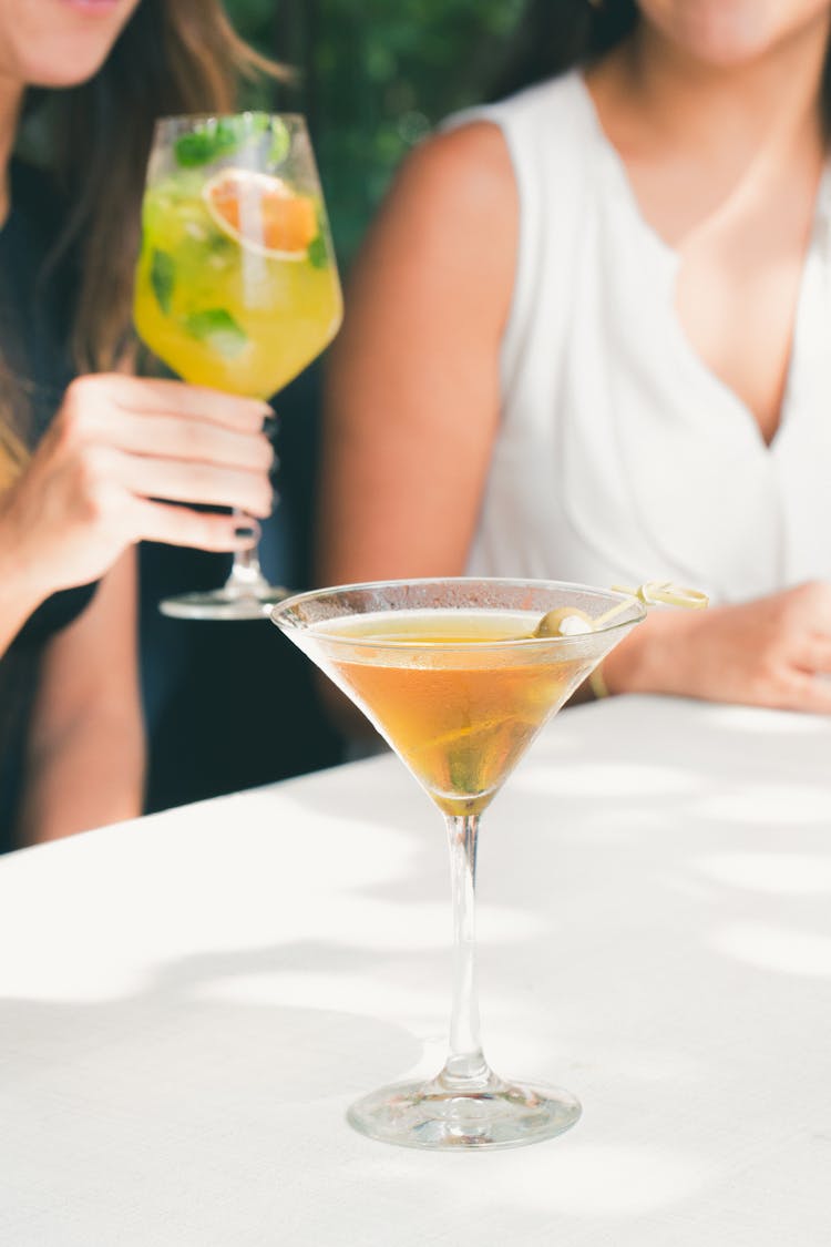 Women Sitting At Table Having Cocktails