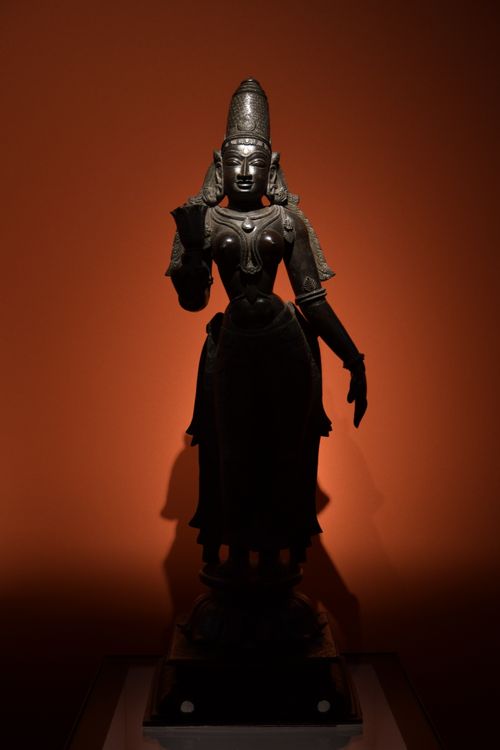Free Intricately crafted bronze sculpture of a Hindu goddess in a museum exhibit with dramatic lighting. Stock Photo