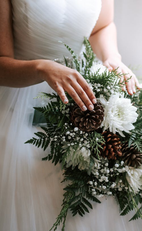 Free Woman in White Wedding Dress Holding White Flowers Stock Photo