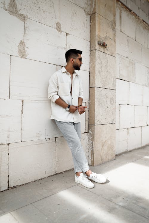 Bearded Man in White Long Sleeves Leaning on the Wall while Looking Afar