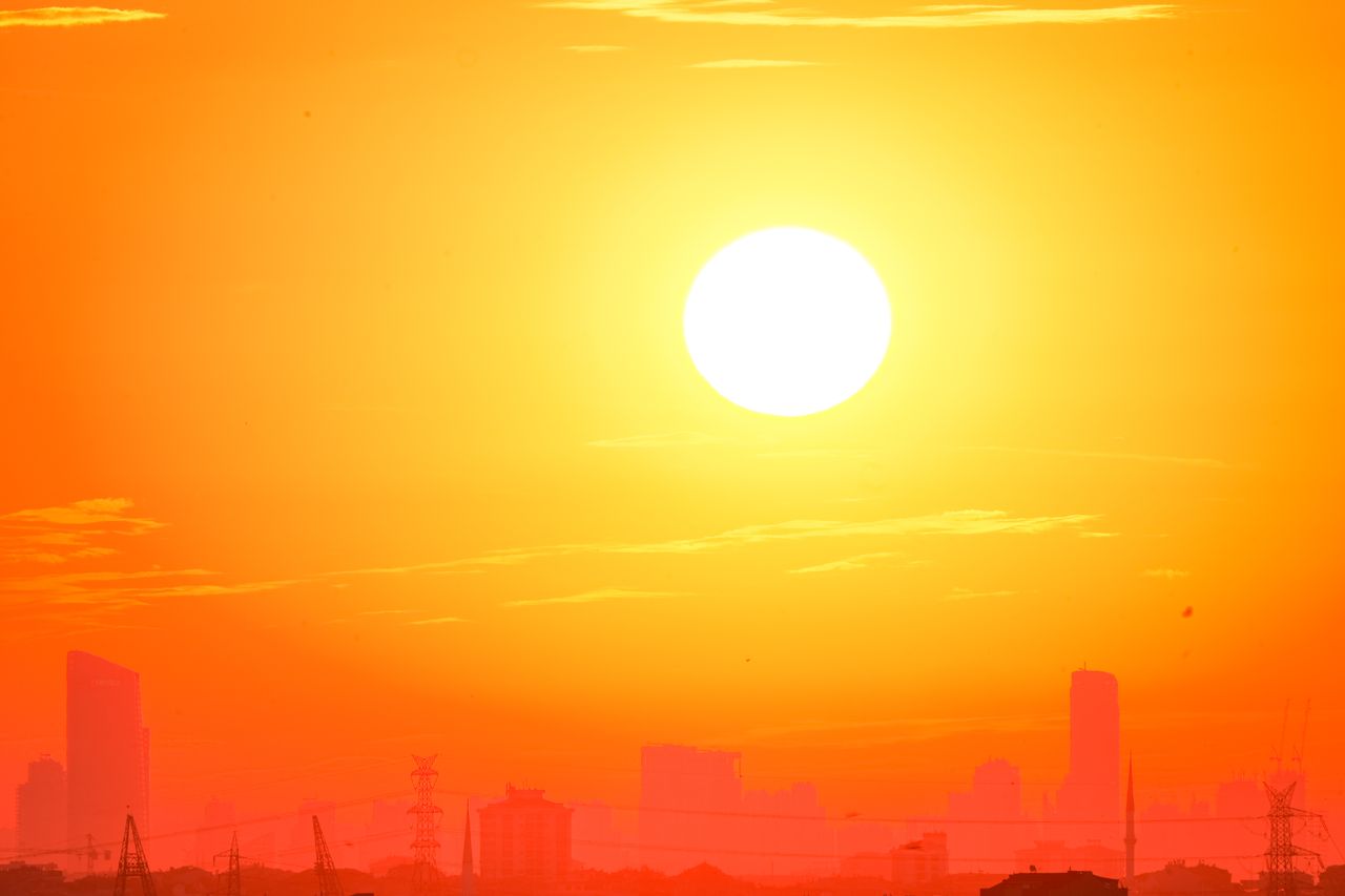 Horizonte de una ciudad recortado contra un vívido cielo anaranjado al atardecer