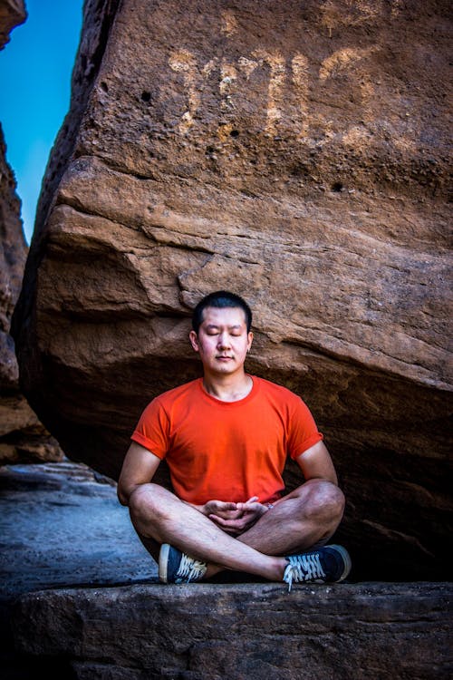 Free Man Meditating Under Rock Stock Photo