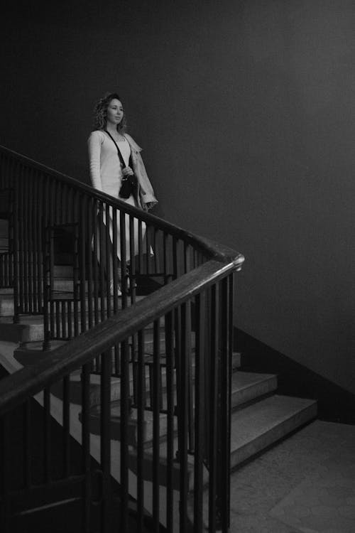 Grayscale Photo of a Woman Walking Down the Stairs