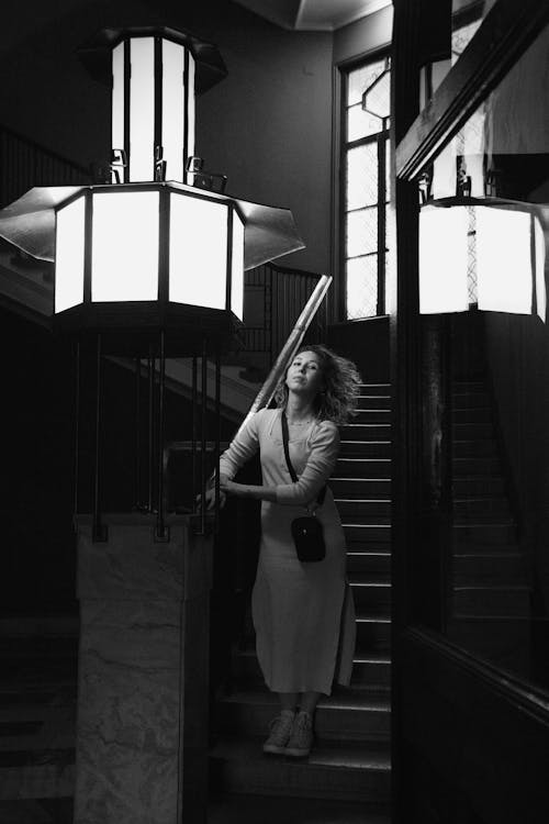 Grayscale Photo of a Woman Standing on the Stairs
