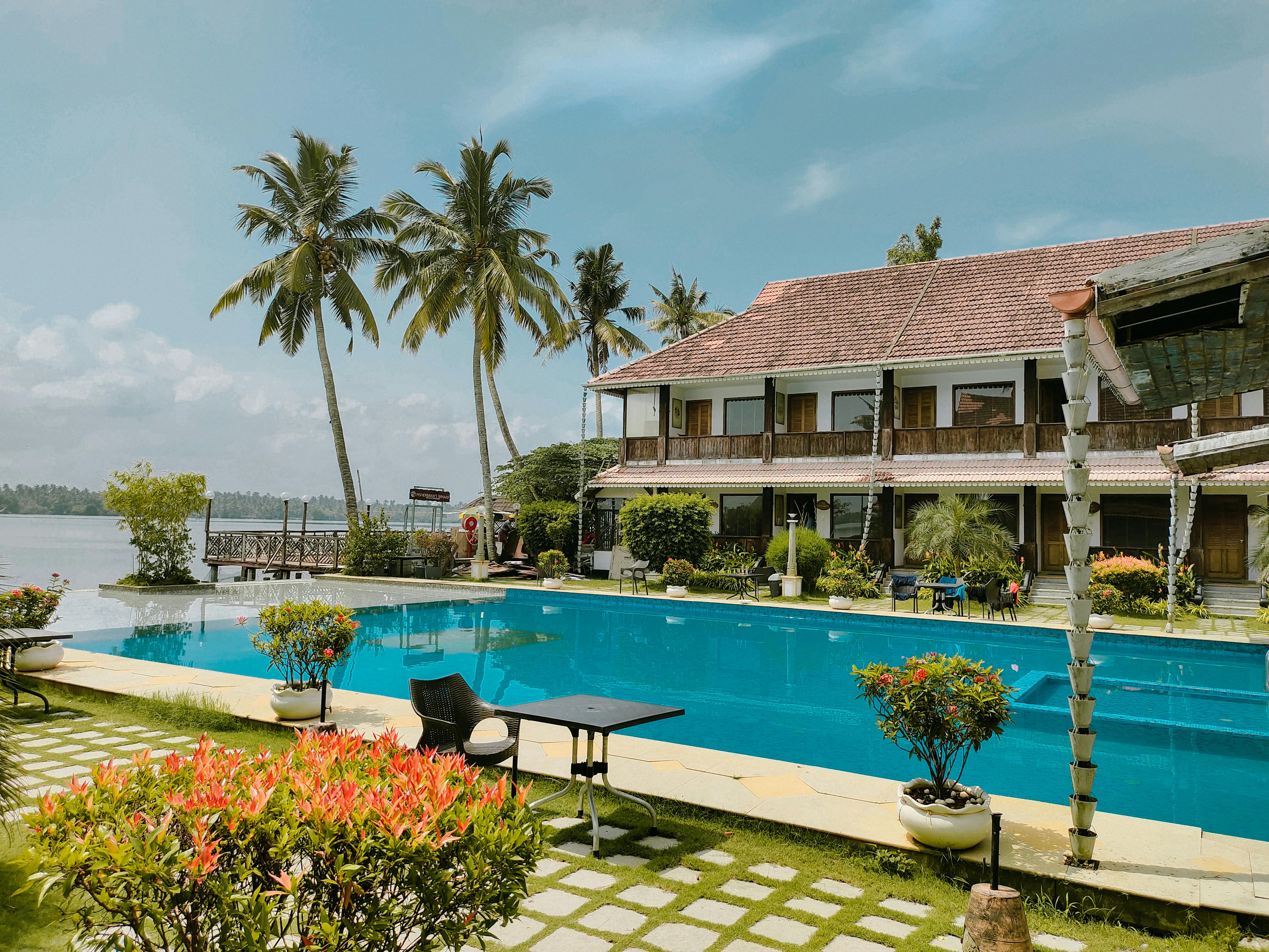 Elegant resort in Kochi, India featuring a pool surrounded by lush coconut trees, perfect for a tropical getaway. - Photo by Akshay Mr on Pexels