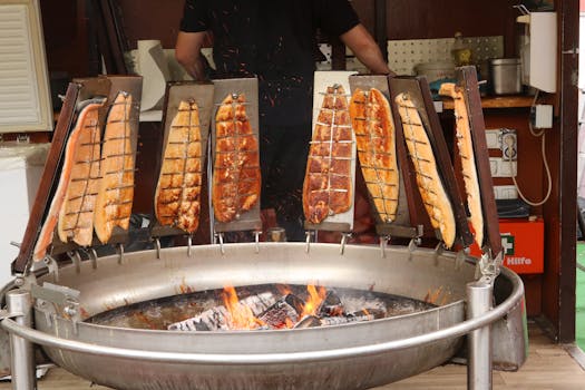 Fresh fish fillets grilling over an open fire at a traditional German festival.