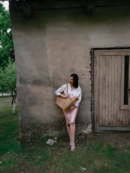 Woman in White Long Sleeve Shirt Carrying a Straw Bag