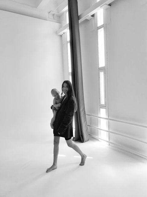 A mother holding her baby in a well-lit studio, capturing tender moments in black and white.