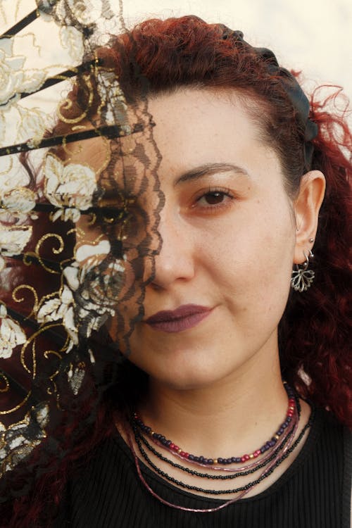 A Lace Hand Fan Covering the Half of the Woman's Face 