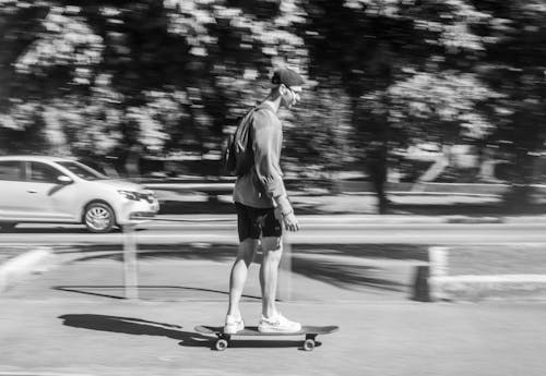 Grayscale Photography of a Man Riding a Skateboard on the Street