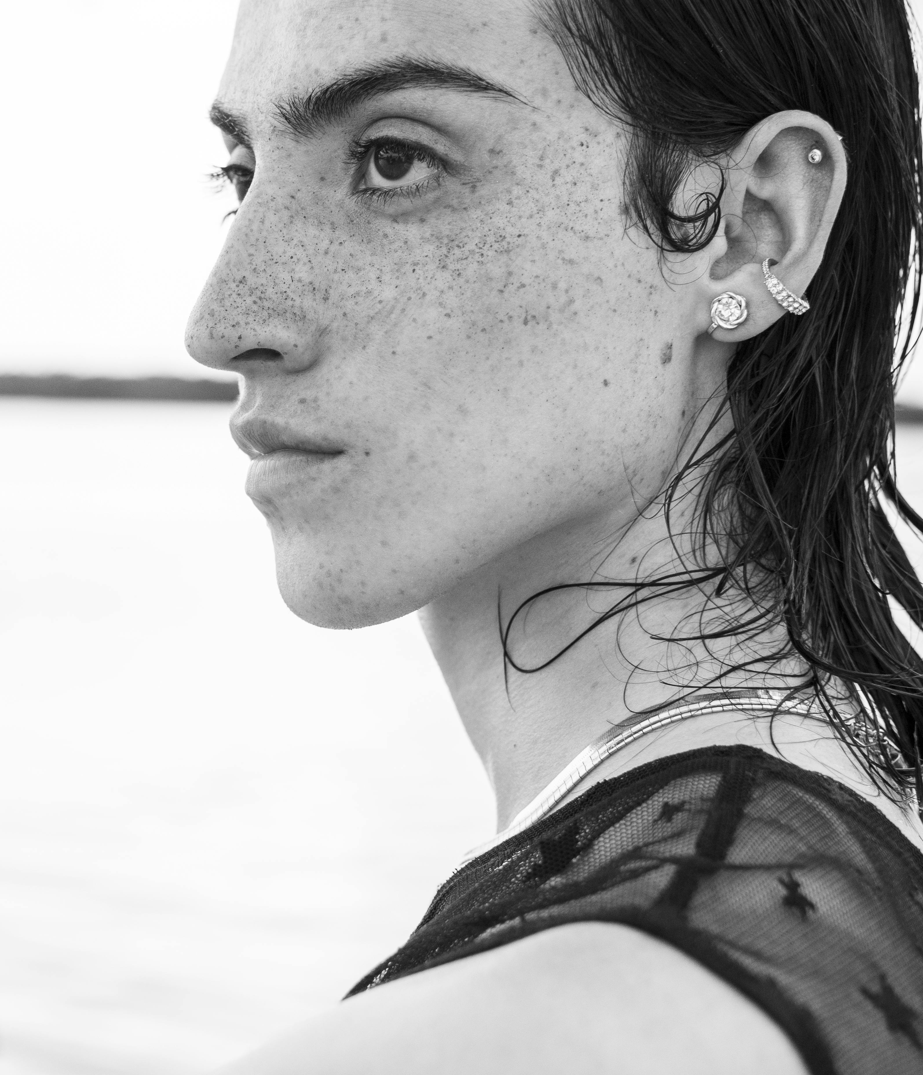 Artistic side profile portrait of a young woman with earrings in black and white.