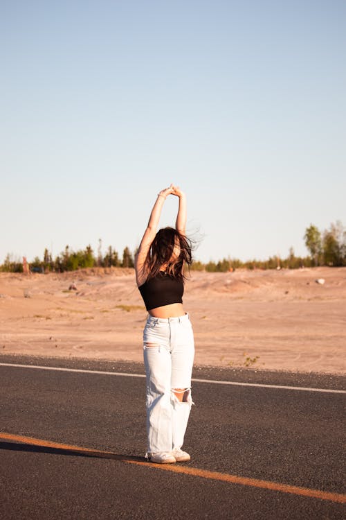 Woman in Black Shirt and Ripped Jeans Standing on the Road