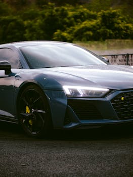 Close-up of a modern sports car parked outdoors with headlights shining.