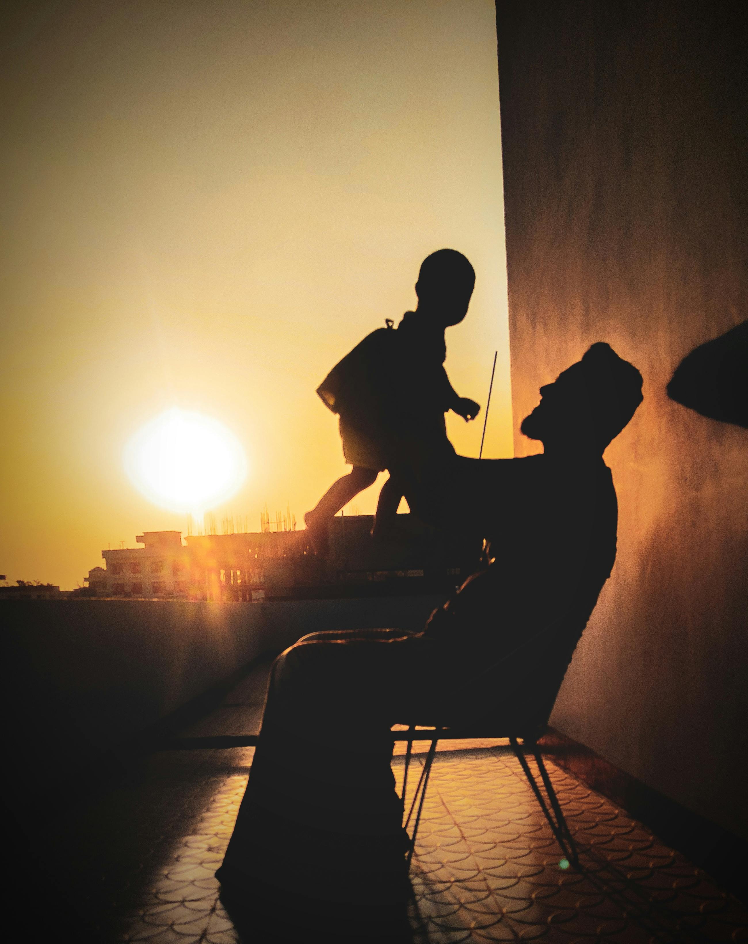 A silhouette of a father lifting his child against a stunning sunset backdrop, capturing a joyful moment.