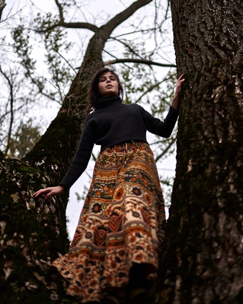Woman in Black Turtle Neck Long Sleeves and Long Skirt on Tree Trunk 
